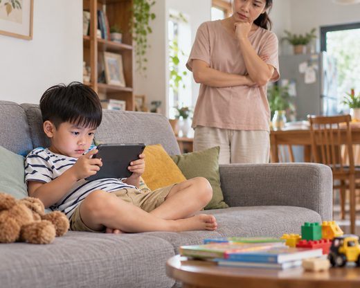 Bé mải mê chơi máy tính bảng, mẹ lo lắng đứng sau